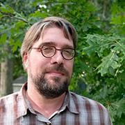 A photo of Michael Walsh st和ing outside in front of a tree