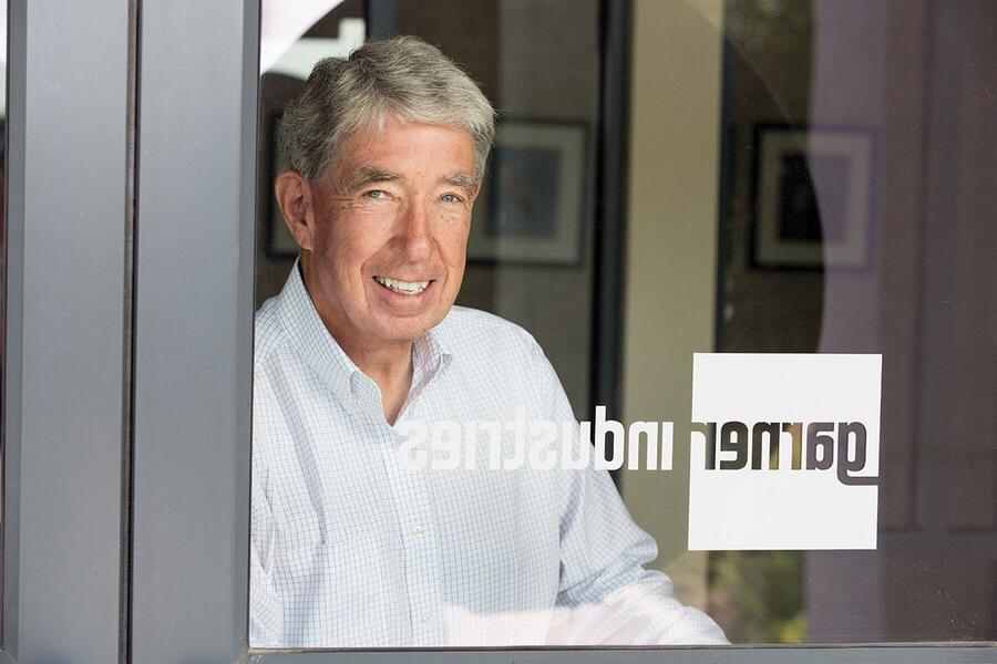 Head shot of Philip Mullin behind a glass door with a logo that says, Garner Industries.