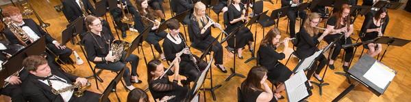 Orchestra students playing their instruments during a music concert.