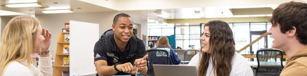 Four students sitting and talking to each other in the NWU library.