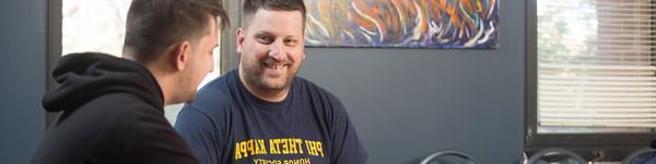 Two male students in a room. One student's shirt reads, Phi Theta Kappa Honor Society.