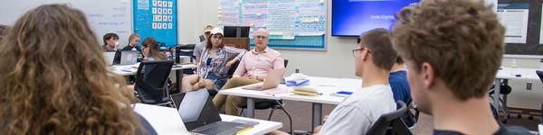 A seated Professor Johnathan Redding lecturing to a class full of students.