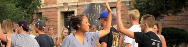 College students high-five while walking on campus.