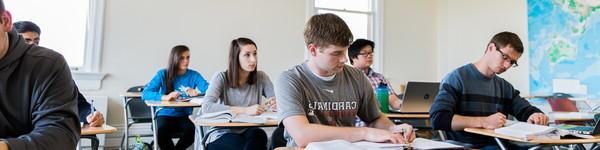 Male and female students sitting in desk in a classroom.