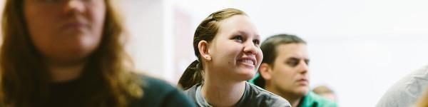 Students sitting in class looking up and smiling.