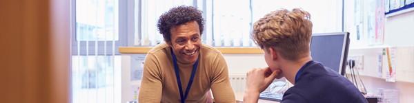 An adult male counselor speaks to a male student.