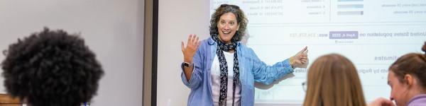 Professor Borchardt lectures to her class while pointing to a screen.